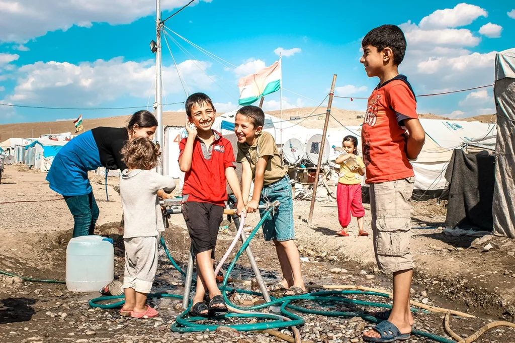 Børn og familier i et flygtningeområde med fokus på fællesskab, rent vand og humanitær støtte